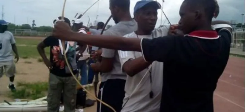 Young archers being coached with recurve bows on an outdoor range in Nigeria
