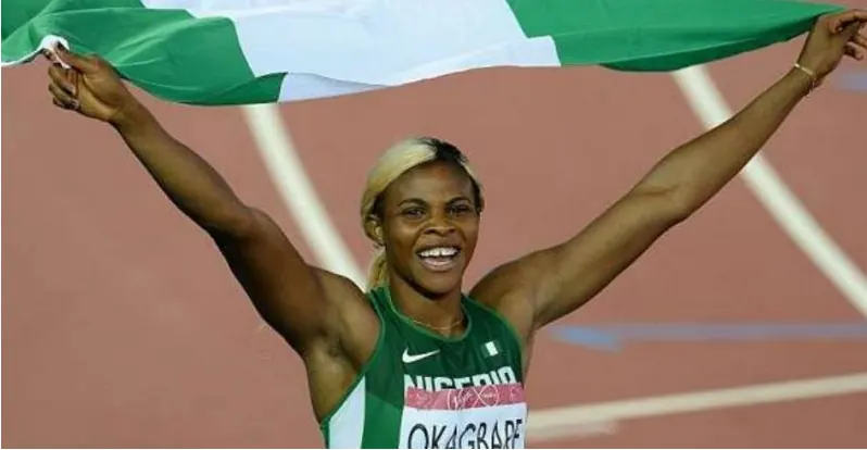 A Nigerian sprinter celebrating with the national flag