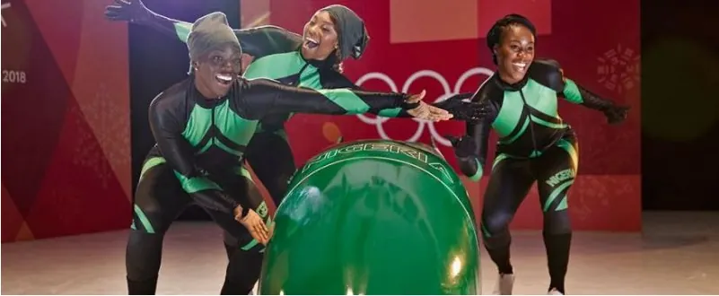 Nigeria's three Olympic bobsledders in green and black race suits posing behind a green sled