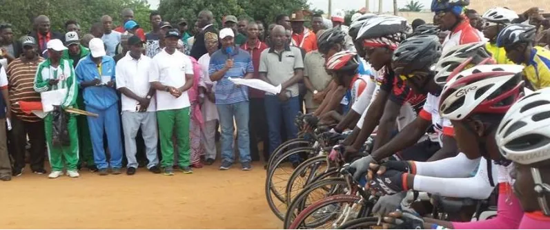 Cyclists lined up at the start of a Nigerian race with officials behind
