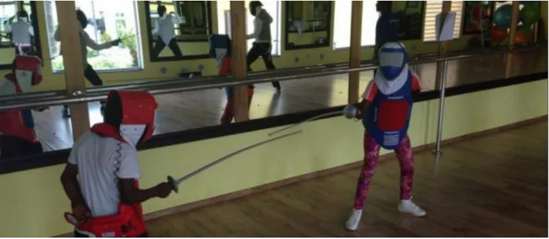Children in fencing masks and jackets practising with foils in a mirrored training hall