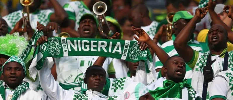 Nigerian football fans with a green NIGERIA scarf and trumpets