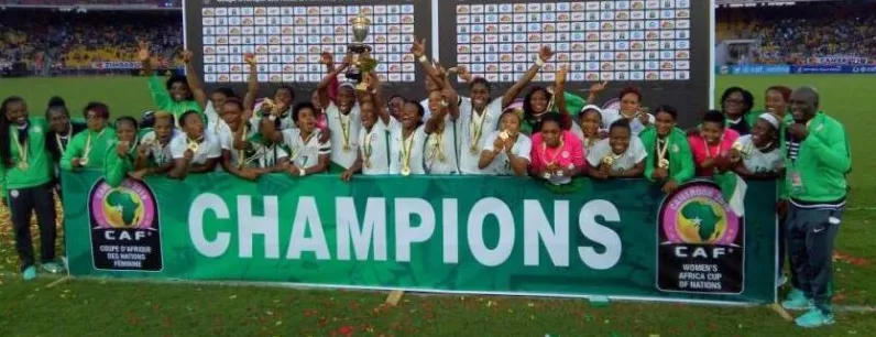 The Super Falcons celebrating behind a CAF CHAMPIONS banner