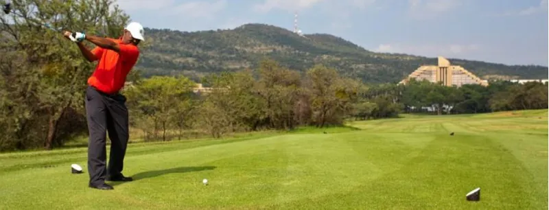 A golfer teeing off on a hillside course