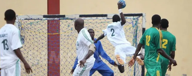 A Nigerian player leaping to shoot past a goalkeeper