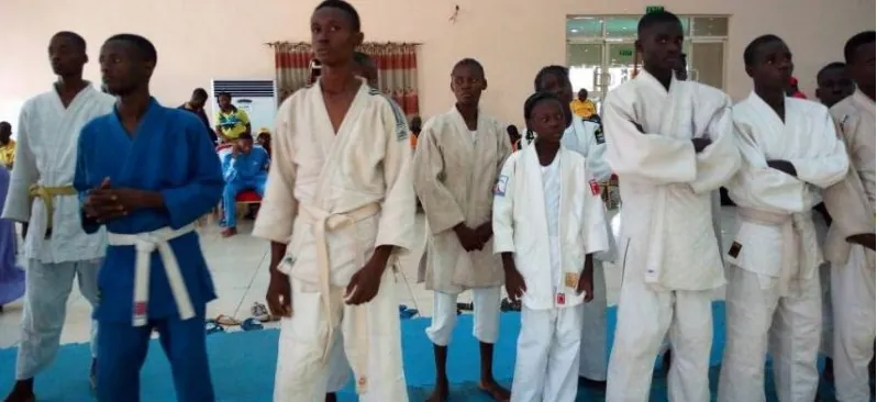 Young Nigerian judokas in white and blue judogi lined up at a tournament