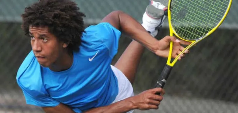 A young player serving in a professional match