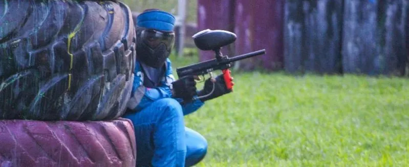 A paintball player taking cover behind tyres