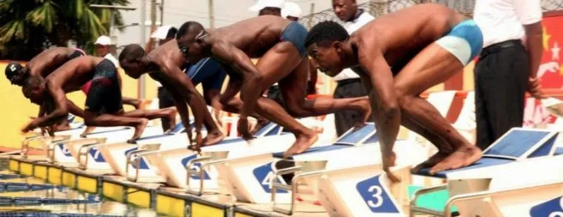 Nigerian swimmers crouch on the starting blocks, ready to dive in