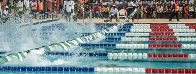 Swimmers racing in a packed Nigerian pool